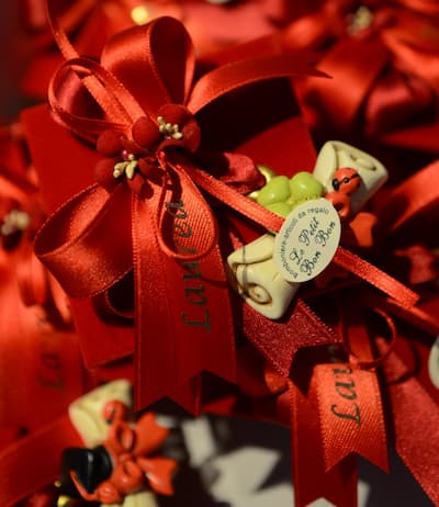 Sacchettini artigianali per laurea con fiocchi rossi, decorazioni floreali, pergamene in miniatura e coccinelle portafortuna.