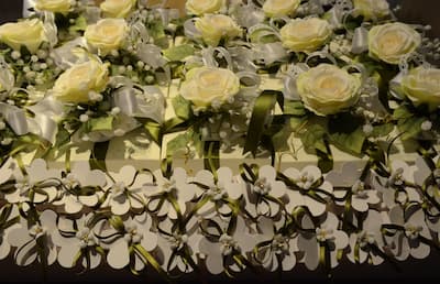 Cesto decorativo con bomboniere per anniversario, rose gialle e bianche artificiali, nastri verdi e argento, dettagli floreali su base intagliata.
