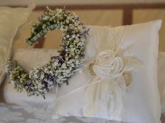 Cuscino con fedi nuziali e corona floreale, simboli di cerimonia e amore