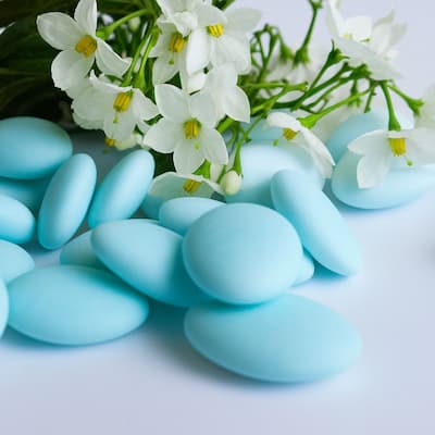 Confetti azzurri lisci con decorazione floreale bianca, ideali per battesimo provenienti da rinomate aziende dolciarie italiane.