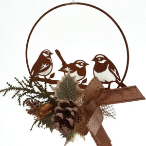 Decorazione natalizia in metallo marrone a forma di cerchio con silhouette di tre uccellini su un ramo. Ornamento arricchito da pigne, rami di pino e fiocco rustico color bronzo.