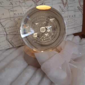 Globo in cristallo trasparente con incisione 3D del Sistema Solare, pianeti e orbite etichettate, illuminato da una base LED circolare in legno.