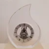 Orologio da tavolo a forma di goccia in cristallo con ingranaggi a vista e numeri romani, collezione Rinoldi.