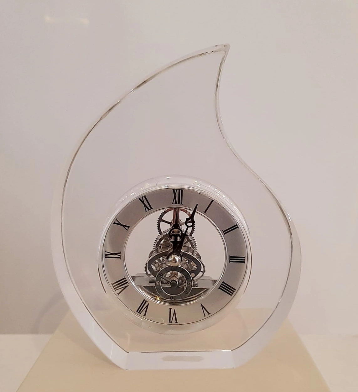 Orologio da tavolo a forma di goccia in cristallo con ingranaggi a vista e numeri romani, collezione Rinoldi.